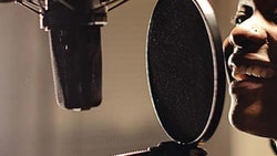 Individual with headphones speaking or singing into a microphone at a recording studio for medbridge.