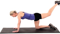 A person in workout clothes on a black mat does a donkey kick exercise for medbridge.