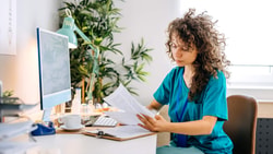 Healthcare professional reviewing billing documents at desk, illustrating use of GP modifier, KX modifier, and GA modifier.