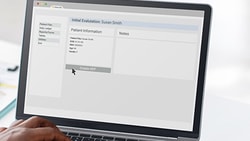 Healthcare professional using a laptop to assign a home exercise program through an EMR-integrated patient engagement platform.