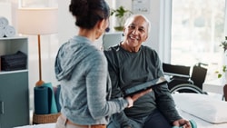 A physical therapist uses a tablet to review a digital home exercise program with a senior Medicare patient during a one-on-one rehabilitation session.