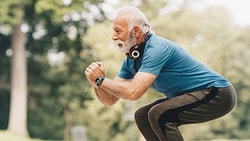 Older adult performing a squat exercise outdoors, demonstrating physical activity for knee osteoarthritis management.