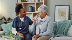Speech-language pathologist assisting patient with safe swallowing techniques during dysphagia management therapy.