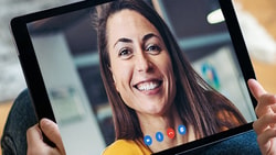 Tablet showing a video call with a smiling woman in a yellow top, using medbridge.