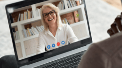 A medbridge video call shows a smiling person with short hair and glasses on a laptop screen.