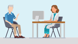 In a medical office, an elderly man in a blue shirt speaks with a female doctor at her desk.