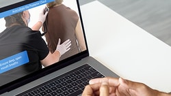 Healthcare professional watches clinical training video on a laptop to support onboarding and skill development.