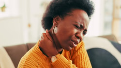 black woman holding neck in pain - neck disability index