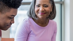 A woman smiles at a young person in a bright room during a medbridge session.