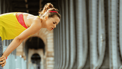 Woman in athletic wear pauses to catch her breath on a medbridge.