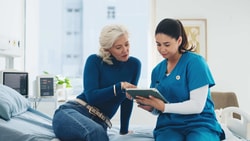 A clinician and patient review data on a tablet in a hospital setting, highlighting modern patient outcomes.