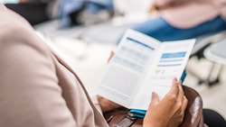 Individual reading a brochure in a Medbridge waiting area.