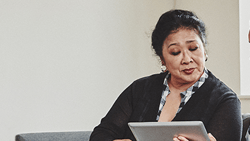 Two women, a Medbridge professional in uniform and another in a black cardigan, sit on a couch looking at a tablet.