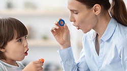 Speech-language pathologist practices speech sounds with a young child using bubbles during a childhood apraxia of speech session.