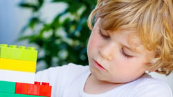 Child focused on assembling colorful blocks indoors.