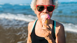 Older adult enjoying cold ice cream by the beach, representing the sensory role of cold in a dysphagia diet.