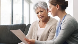 Clinician reviewing a semantic feature analysis worksheet with an older adult during a therapy session at home.