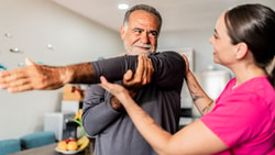 Clinician assisting older adult with shoulder mobility exercise to address anterior shoulder pain.