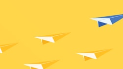 A blue paper airplane leads four yellow ones on a yellow background.