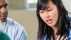 Four people sit in discussion as one woman speaks and gestures.