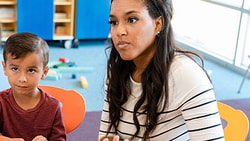 School-based professional talking with a parent and child in a brightly lit classroom, discussing school violence support strategies.