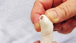 A hand bandaging a finger on light blue fabric, with Medbridge branding.