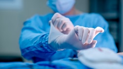 Orthopedic surgeon puts on sterile gloves before an operation in a surgical suite