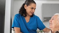 Home health nurse speaking with an older adult patient in a home setting, representing home health care industry trends and support.