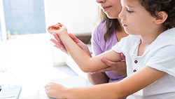 A child on a woman's lap participates in an online doctor consultation via Medbridge.