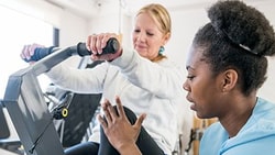 Physical therapist guiding a patient on an exercise bike during treatment for hypermobility spectrum disorder (HSD) or EDS.