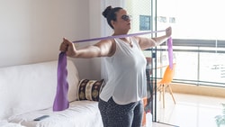Person using a purple resistance band in a living room, visible on medbridge.