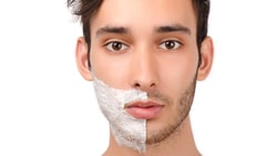 A man with shaving cream on half of his face, highlighting shaved vs. unshaved skin.