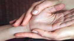 Hands gently holding another's palm, Medbridge style.