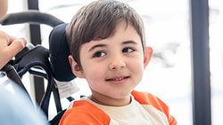 Child in wheelchair looking at clinician, illustrating the importance of head positioning in wheelchair seating support.