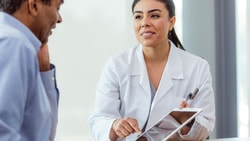 Orthopedic clinician reviews patient-reported outcome results on a tablet with a joint replacement patient during a follow-up visit.
