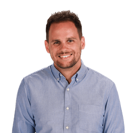 Man smiling in a light blue shirt with short hair and beard, standing against a white background (medbridge).
