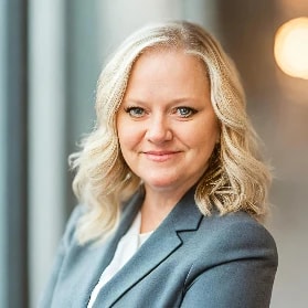 A person with shoulder-length blonde hair in a gray blazer represents medbridge's digital healthcare innovation.
