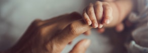 A baby's hand holds an adult's finger, illustrating Medbridge's hybrid care.