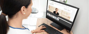 A woman uses a computer displaying medbridge's digital healthcare software.