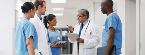 Healthcare professionals in scrubs and lab coats discuss patient care using medbridge software in a hospital hallway.