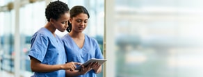 Two medbridge professionals in blue scrubs review a tablet together.