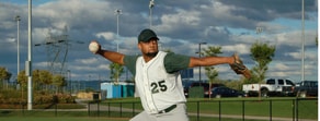A baseball player in a green and white uniform pitches on a field, symbolizing precision like medbridge healthcare training.