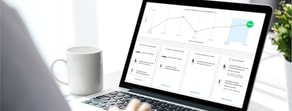 A laptop showing a timeline graph and digital healthcare tools on Medbridge sits next to a white mug.