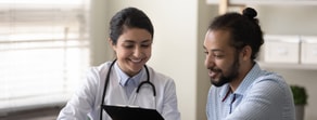 In a bright room, a healthcare professional in a white coat discusses digital healthcare with an attentive man, highlighting medbridge's role.