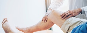 A clinician in a medical coat uses medbridge tools to assess a patient's bent knee.