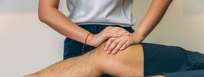 A practitioner gives a knee massage, emphasizing patient care, enhanced by medbridge's digital solutions.