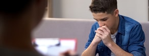 Someone in a healthcare setting looks thoughtful while another holds a clipboard, indicating a medbridge hybrid care discussion.