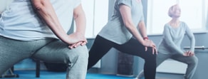 Three individuals in workout attire doing lunges in a fitness studio for a medbridge session.