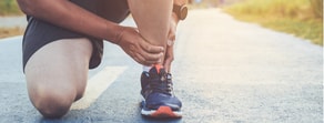 A person in athletic wear ties a running shoe on a sunlit road, symbolizing determination akin to medbridge’s role in digital healthcare.