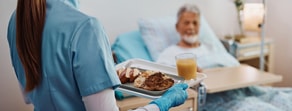 In a hospital, a medbridge-clad worker serves a digital healthcare-integrated meal with nutritious food and juice to a patient in bed.